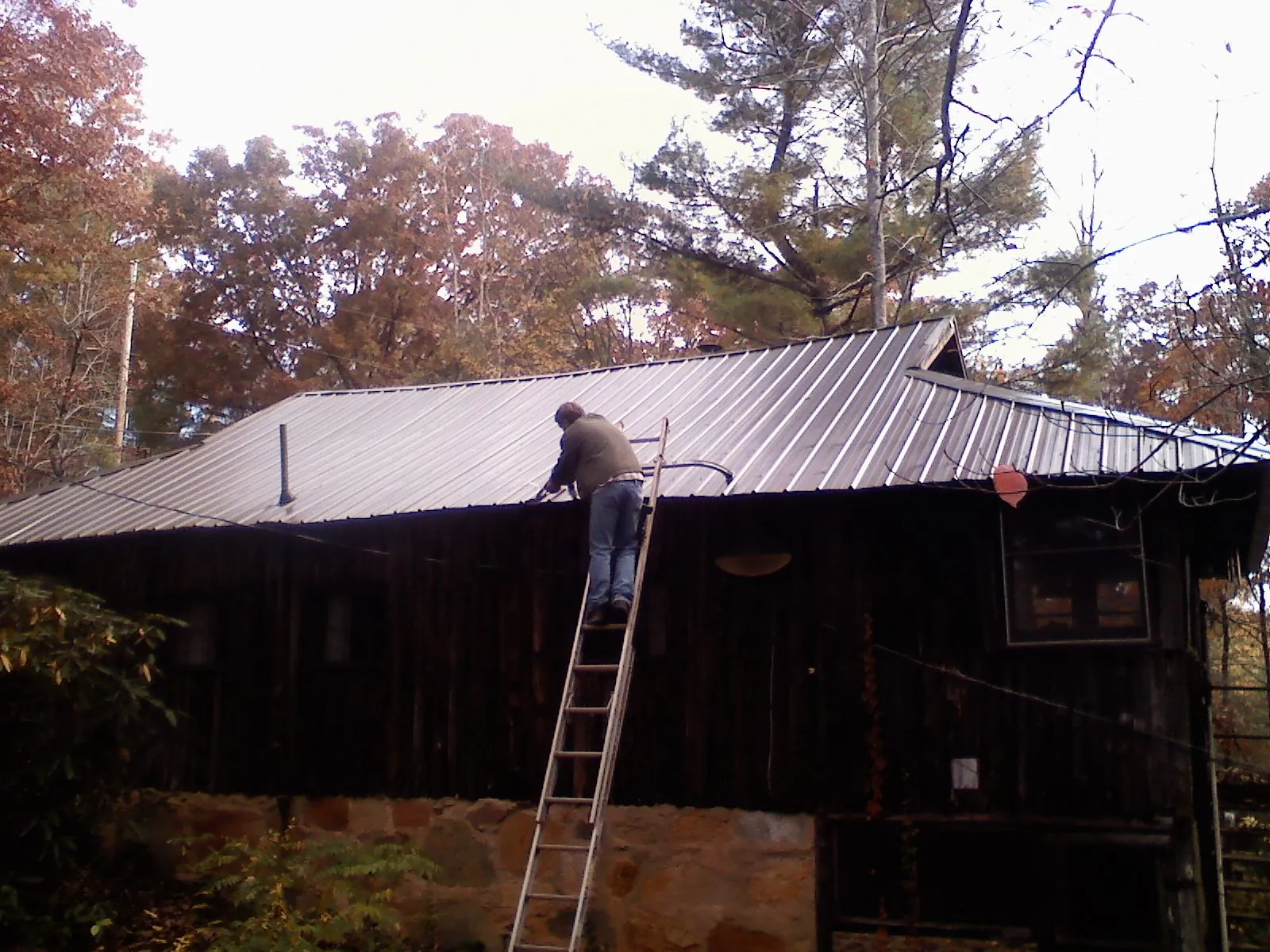 Roofer on a ladder working along the edge of a cabin metal roof in Lincoln